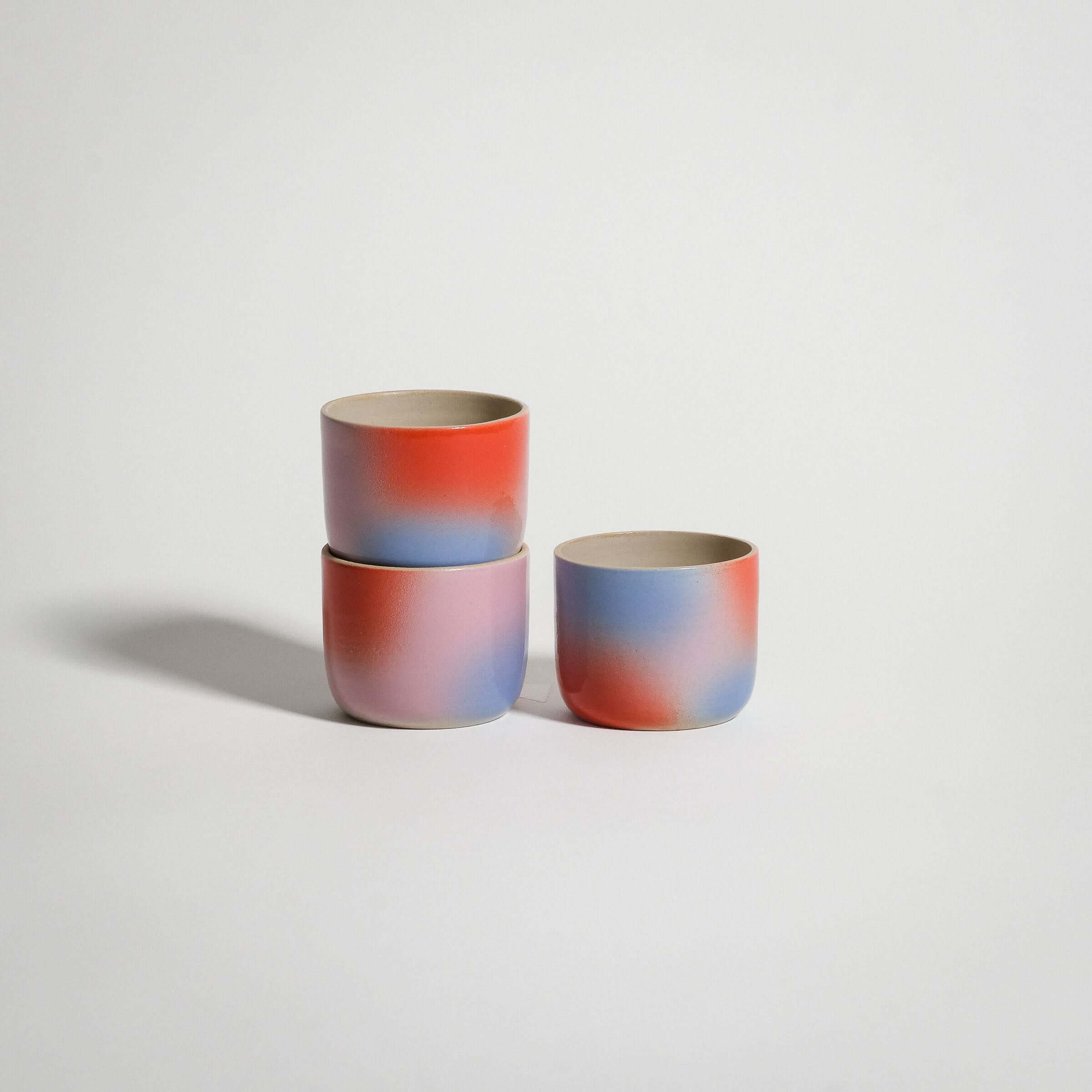 Handcrafted Dawn Espresso Cups in red, blue, and lilac gradient on grey stoneware clay.