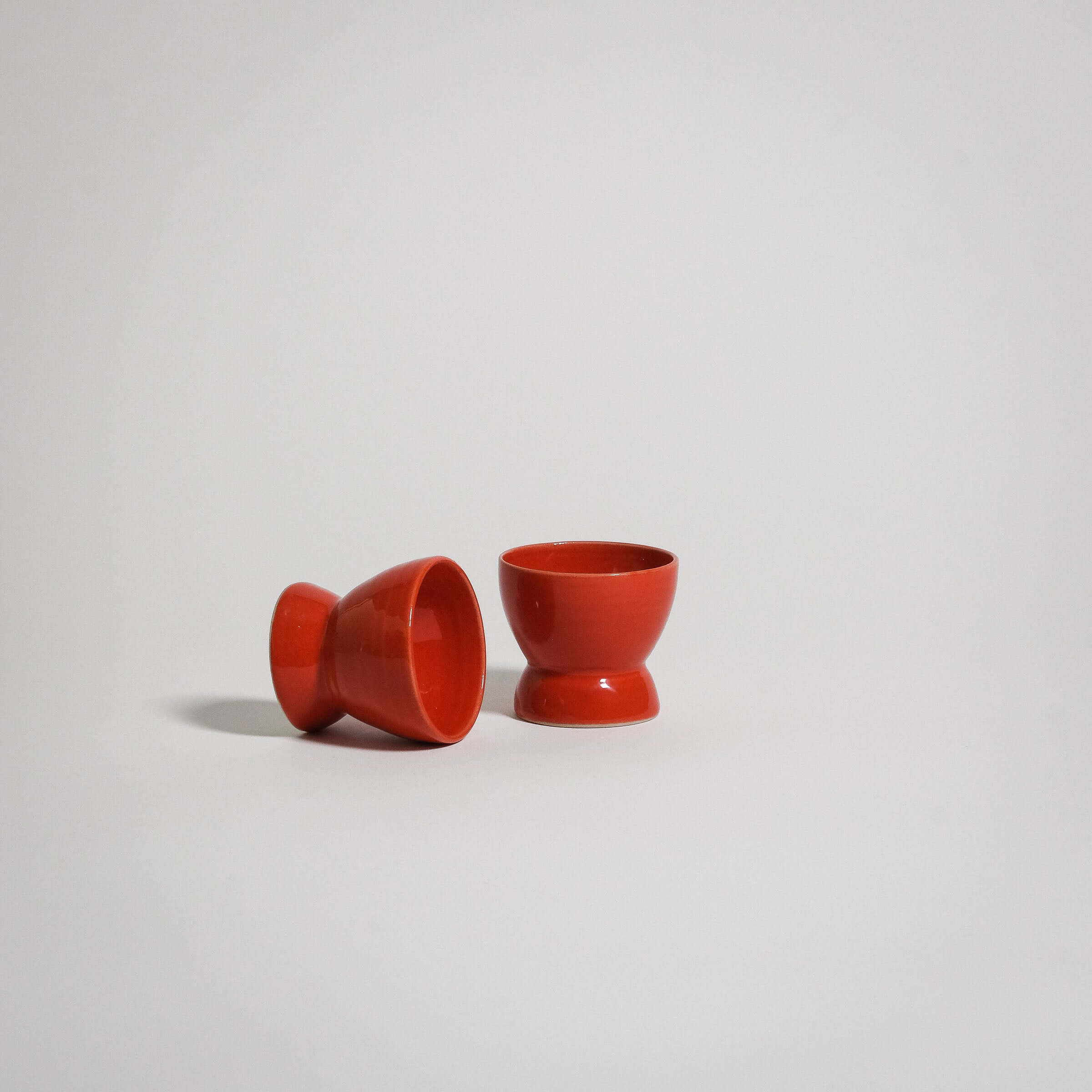 Handmade red egg cups in stoneware, featuring a rich glaze and simple design for everyday use.
