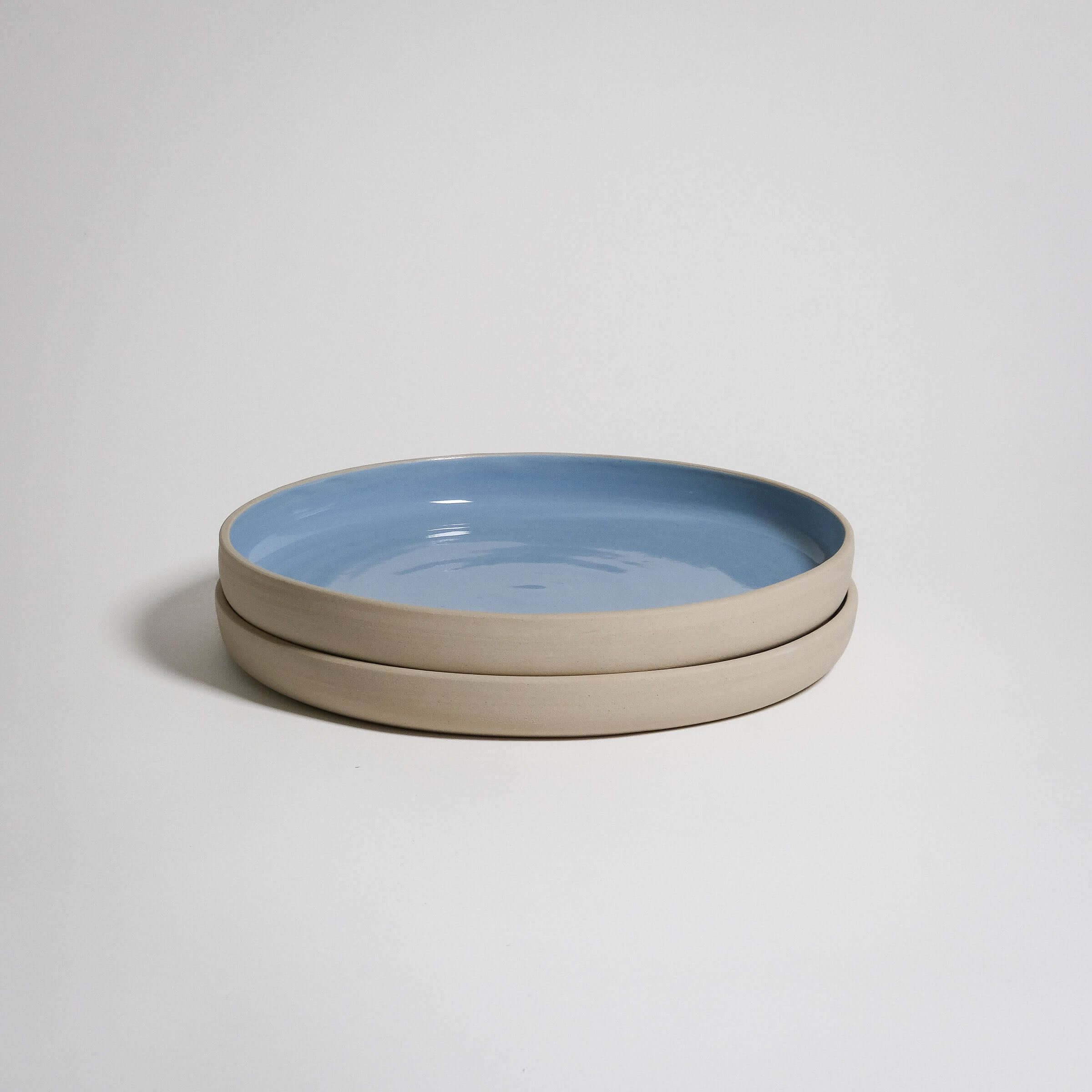 A Medium Plate with a higher rim. The outside is unglazed and the surface is glazed in blue glaizing