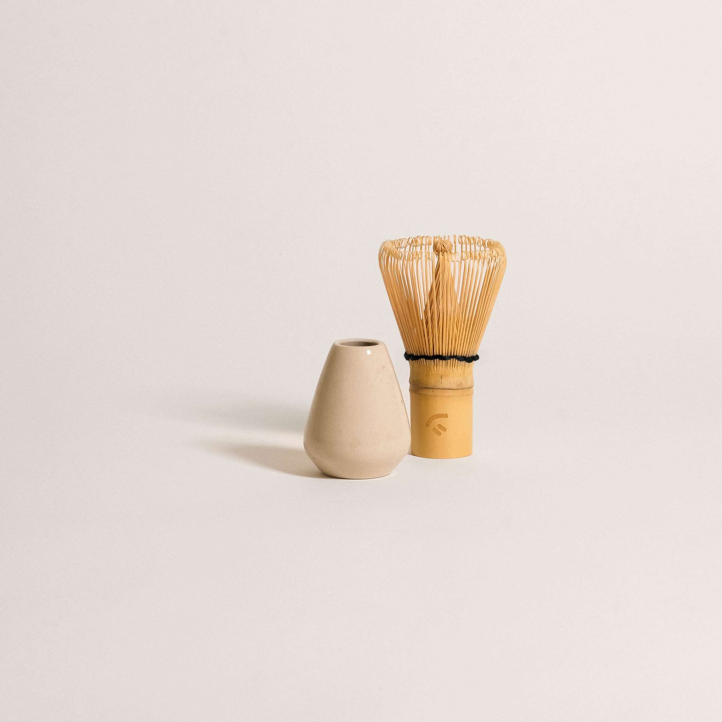 Matcha whisk holder made of grey stoneware clay next to bamboo whisk, perfect for matcha rituals.
