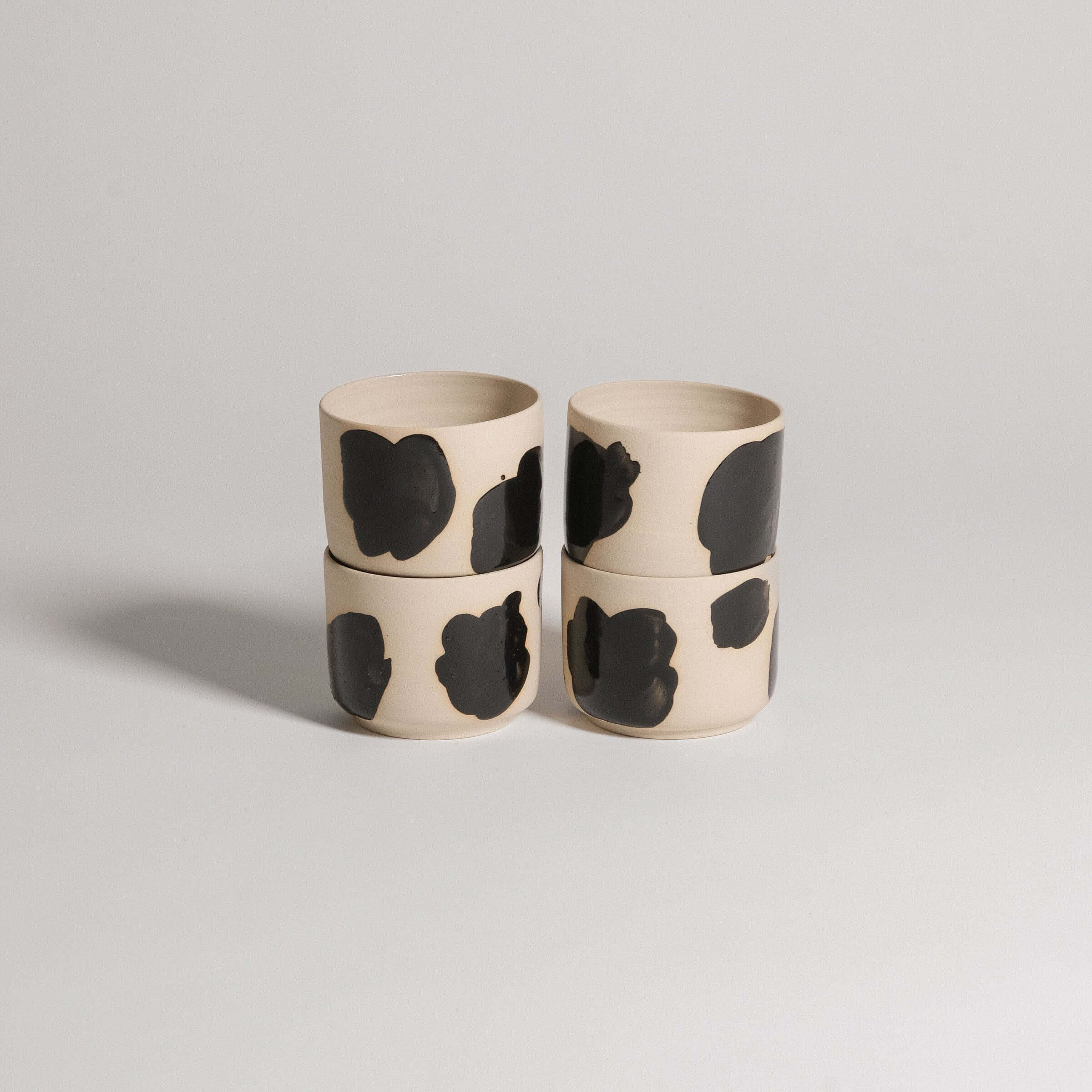 Set of 4 wheel-thrown coffee cups in grey stoneware with glossy black brush strokes, modern and elegant design.