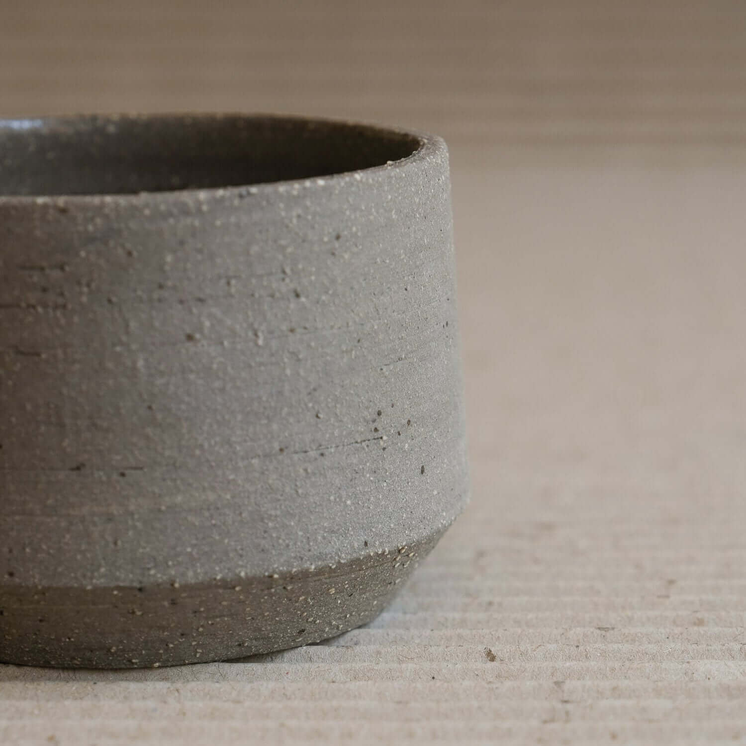 Stoneware Terroir Cup with groggy surface and stone inclusions, showcasing raw exterior and glossy interior.