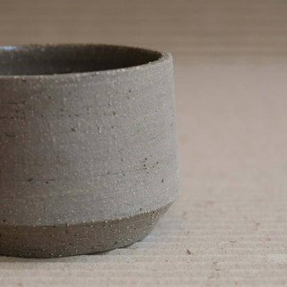 Stoneware Terroir Cup with groggy surface and stone inclusions, showcasing raw exterior and glossy interior.
