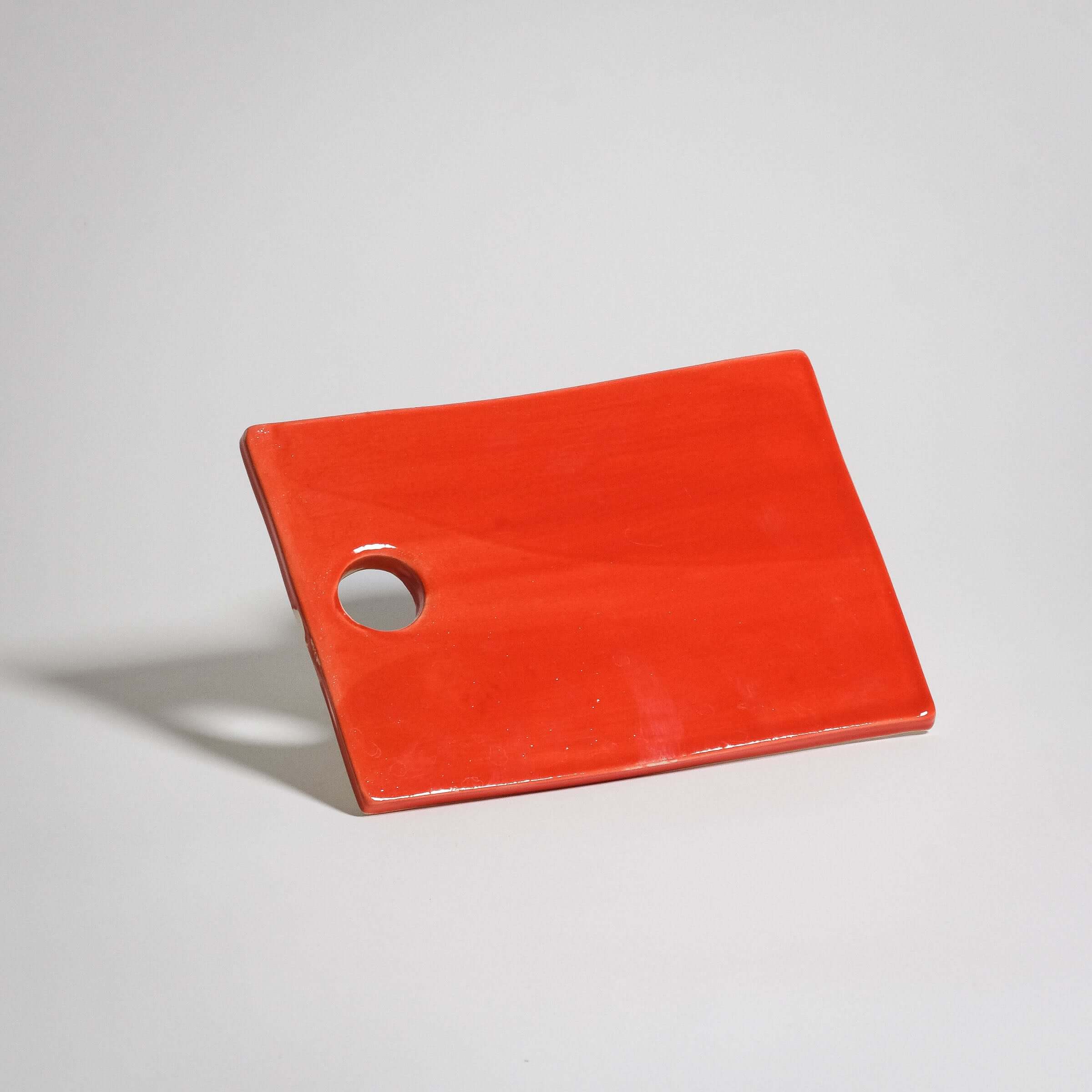 Handmade red serving board made of stoneware with glossy glaze; durable, dishwasher and oven-safe.