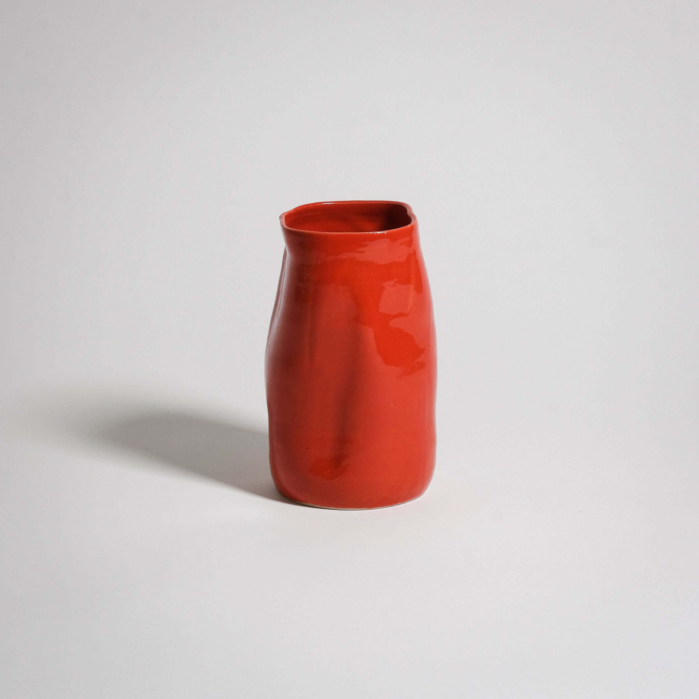 Handcrafted red stoneware vase with a unique shape and glossy finish, perfect for any decor.