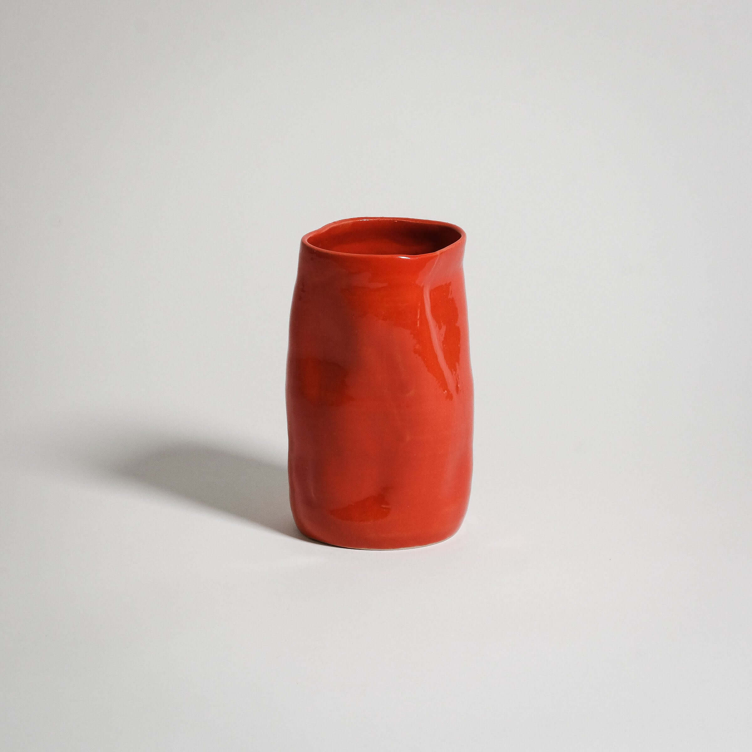Handcrafted red stoneware vase with a unique shape and glossy finish, perfect for any decor.