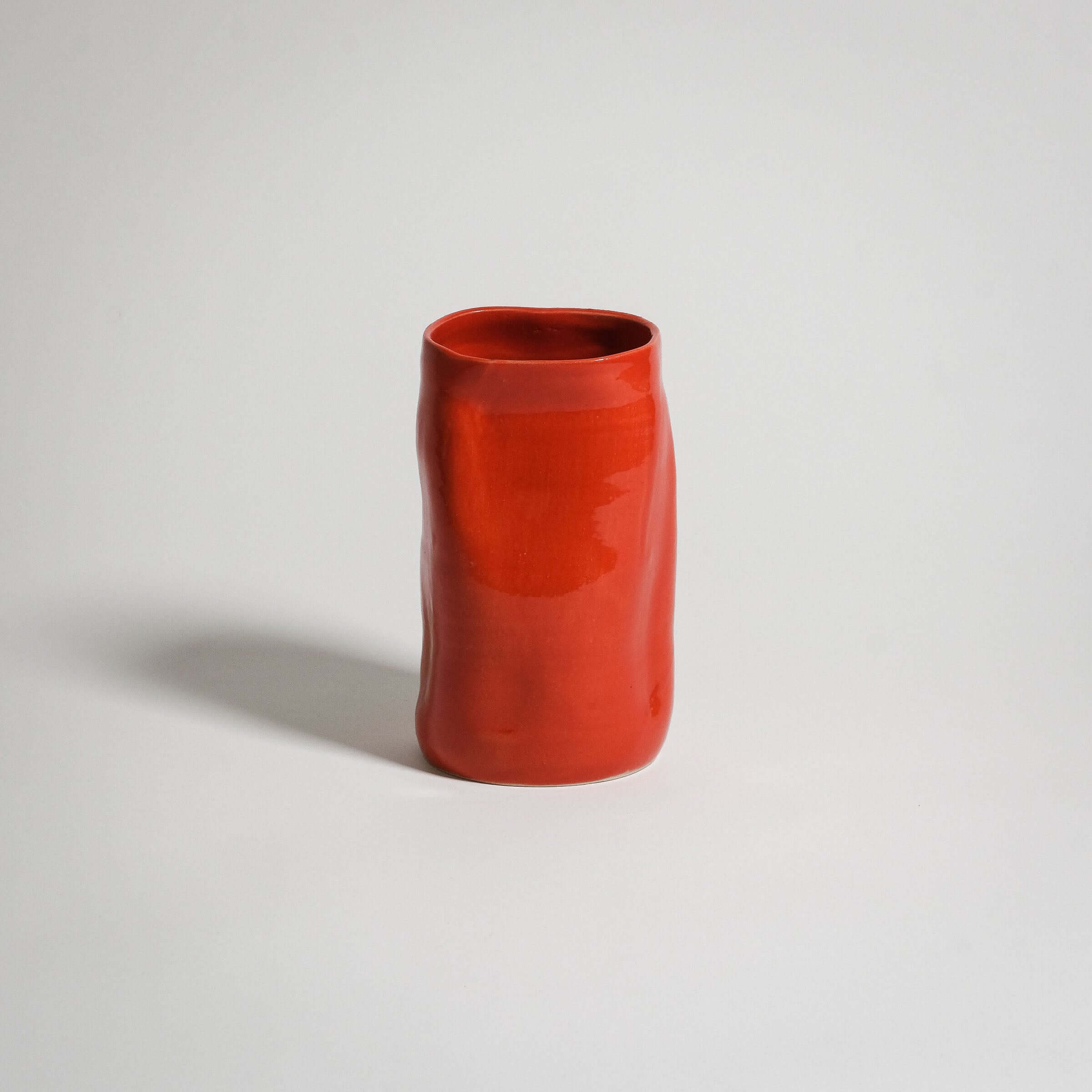 Handcrafted red stoneware vase with a unique shape and glossy finish, perfect for any decor style.
