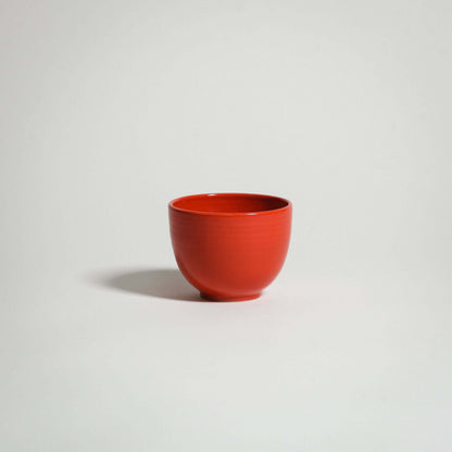 A red ceramic coffee cup side from the side