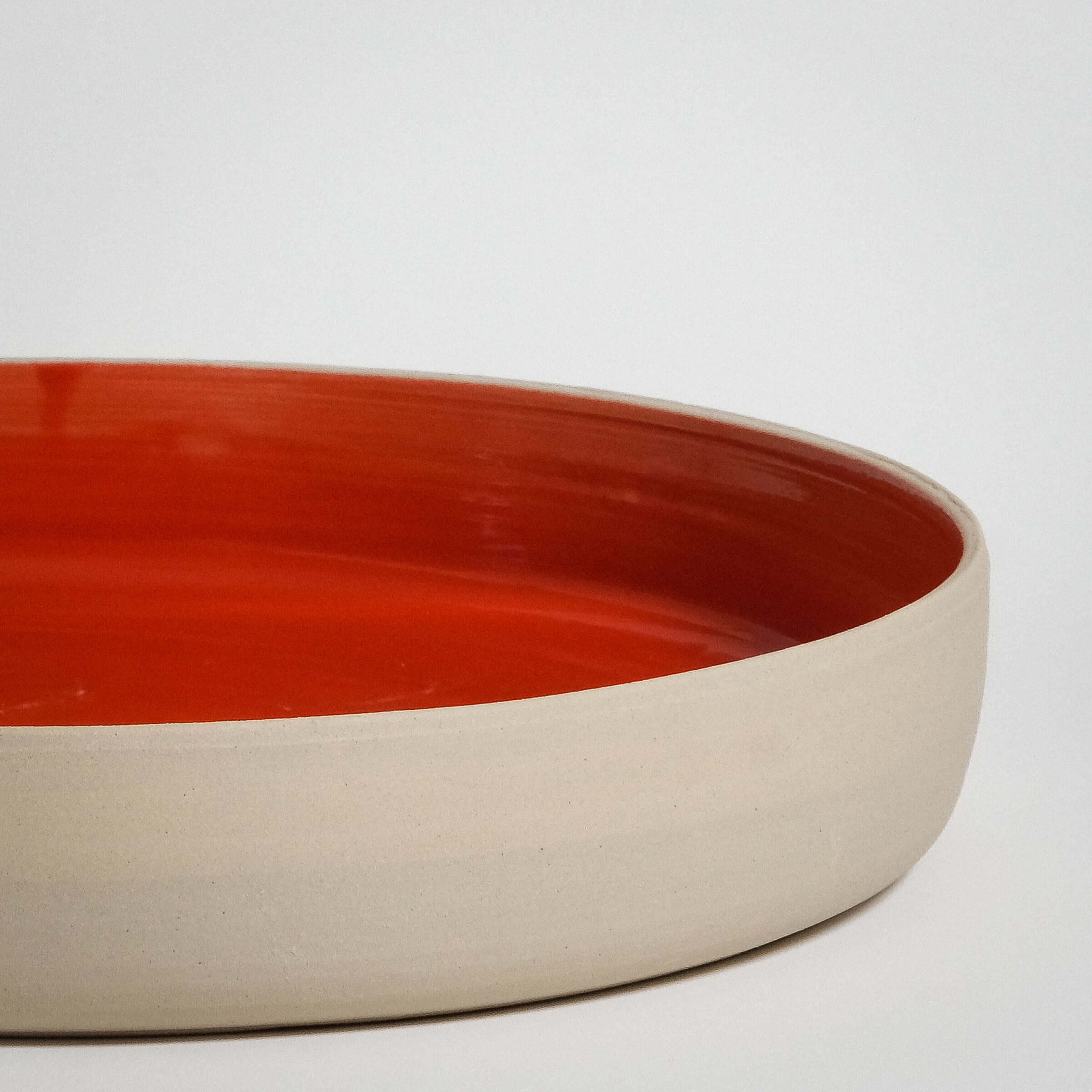 Handmade red stoneware serving bowl with glossy glaze, perfect for food presentation and durable for everyday use.