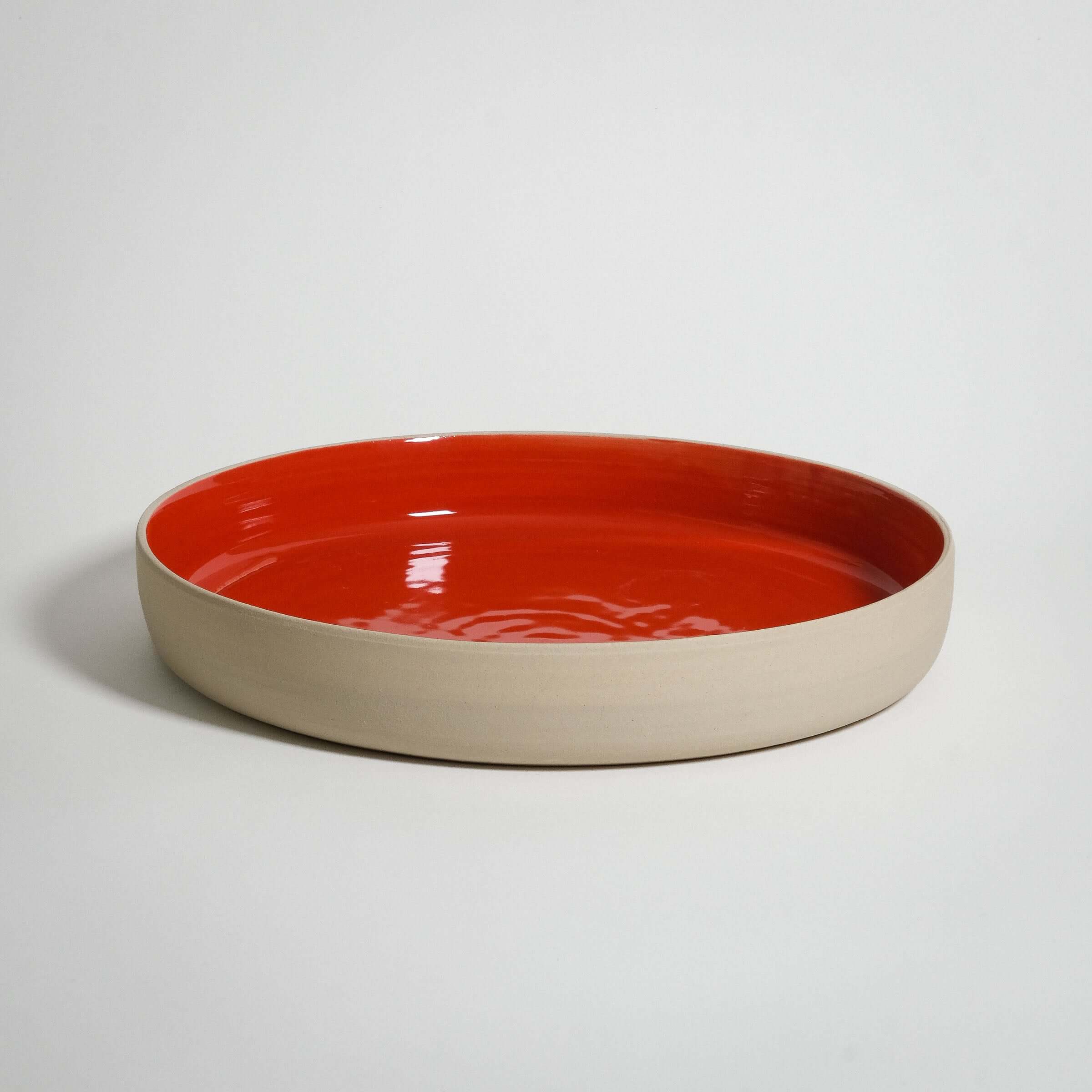 Handmade red serving bowl made of durable stoneware, featuring a glossy glaze for a smooth touch and longevity.