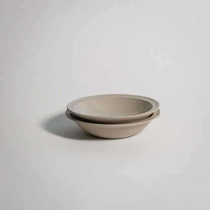 Flat bowl in glossy grey stoneware clay, perfect for small portions, showcasing elegance and craftsmanship.