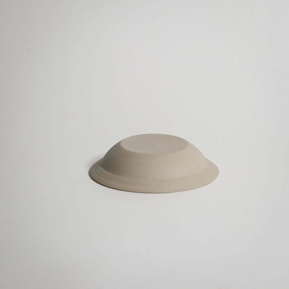 Elegant flat bowl in creme color, made from high-quality grey stoneware, perfect for serving small portions.