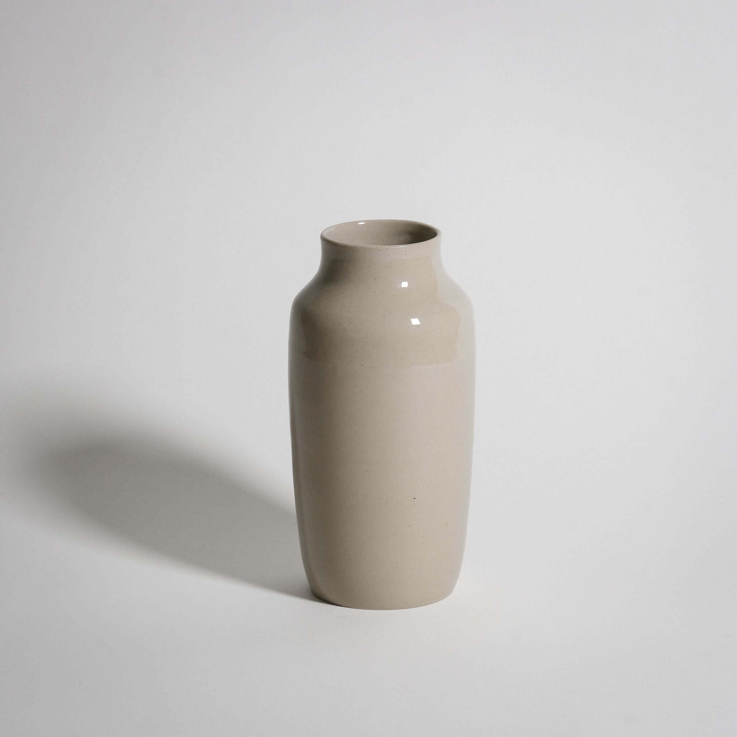Handcrafted medium vase in creme stoneware with glossy glaze, perfect for enhancing any interior decor.