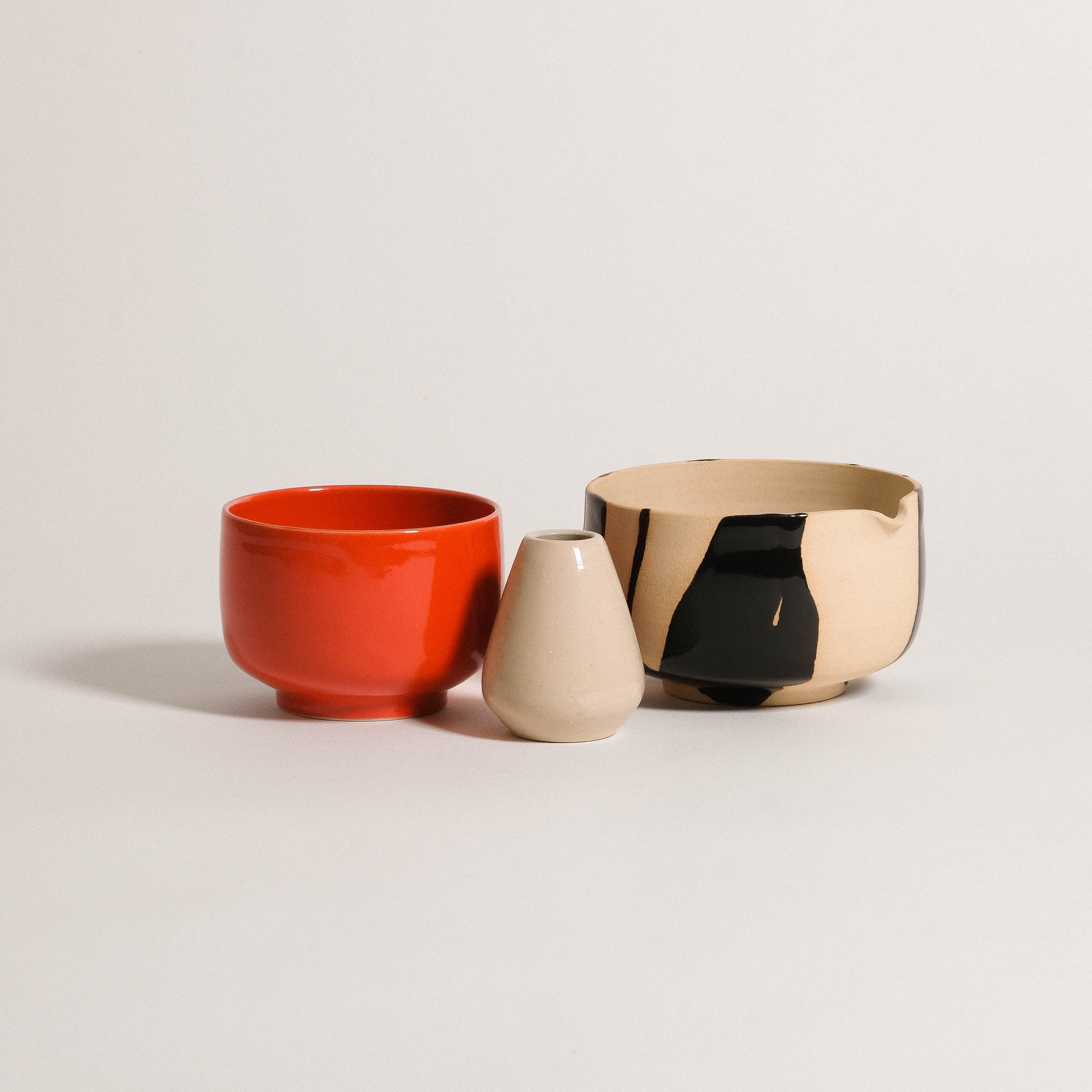 Handcrafted ceramic matcha bowls in red and beige tones, designed for serving and whisking matcha.
