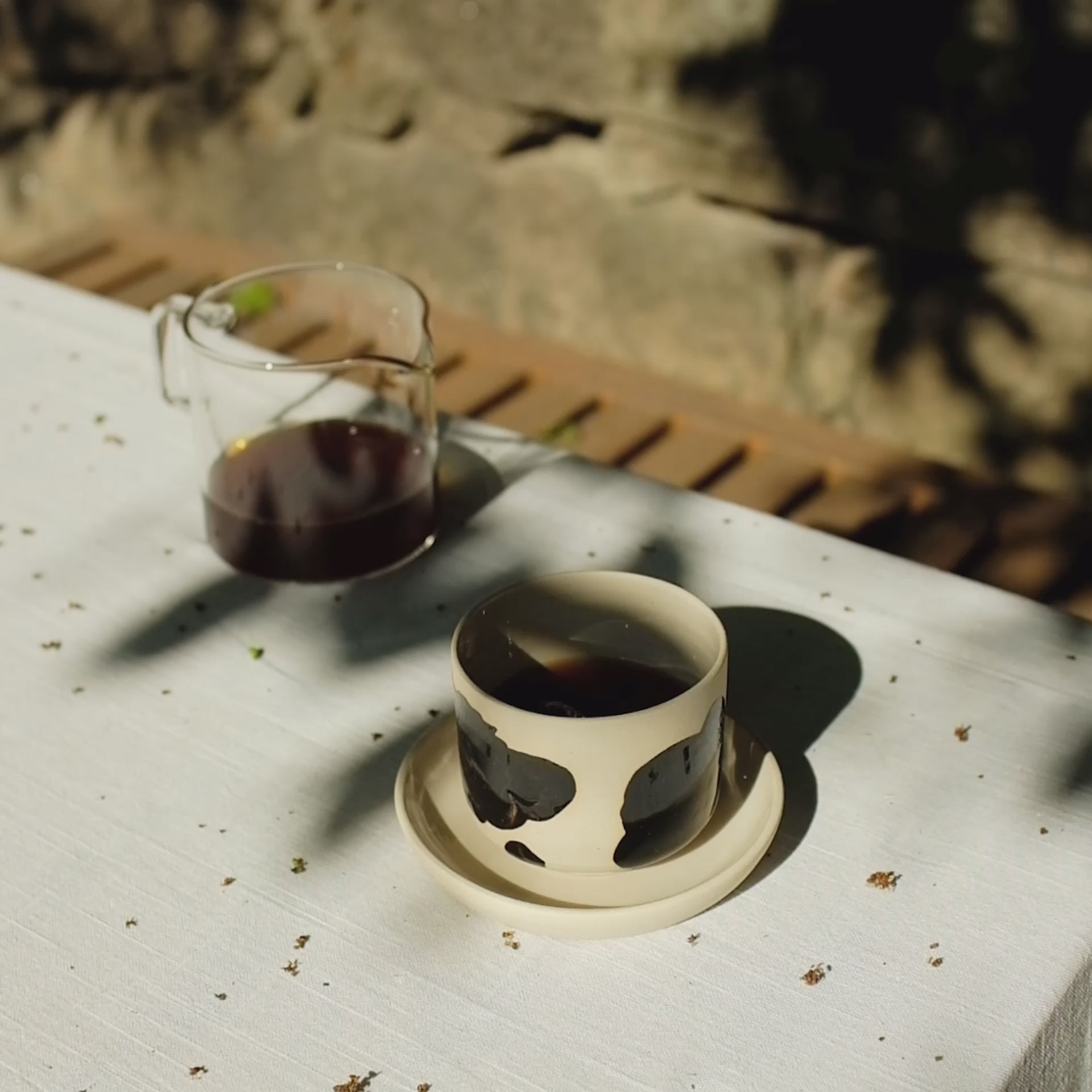 Set of 4 Nomi Pepe coffee cups on a table, showcasing grey stoneware with glossy black brush strokes and clear glaze.