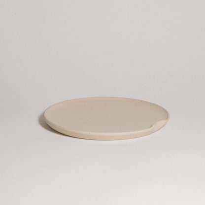 Flat creme dinner plate in grey stoneware with glossy surface, perfect for stylish dining and easy stacking.