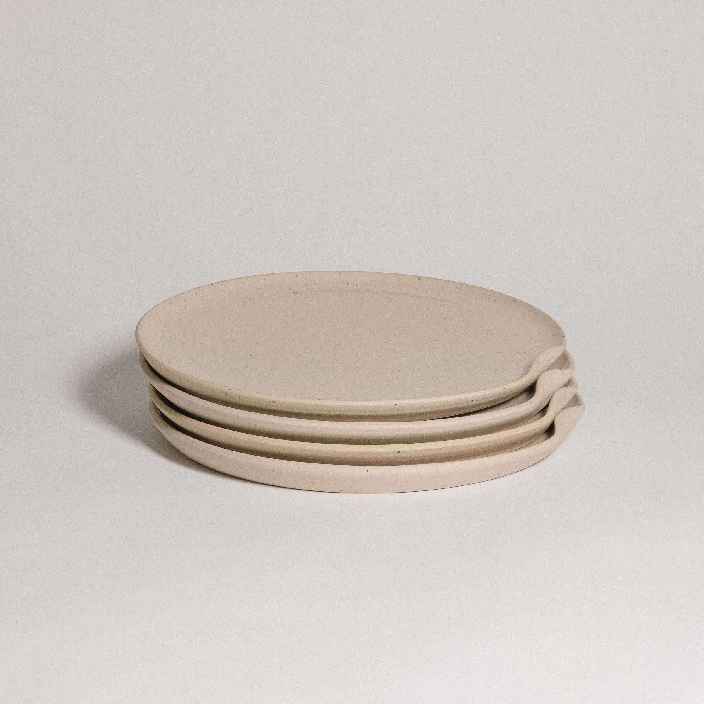 Set of four creme stoneware dinner plates with a glossy finish and easy stacking design.